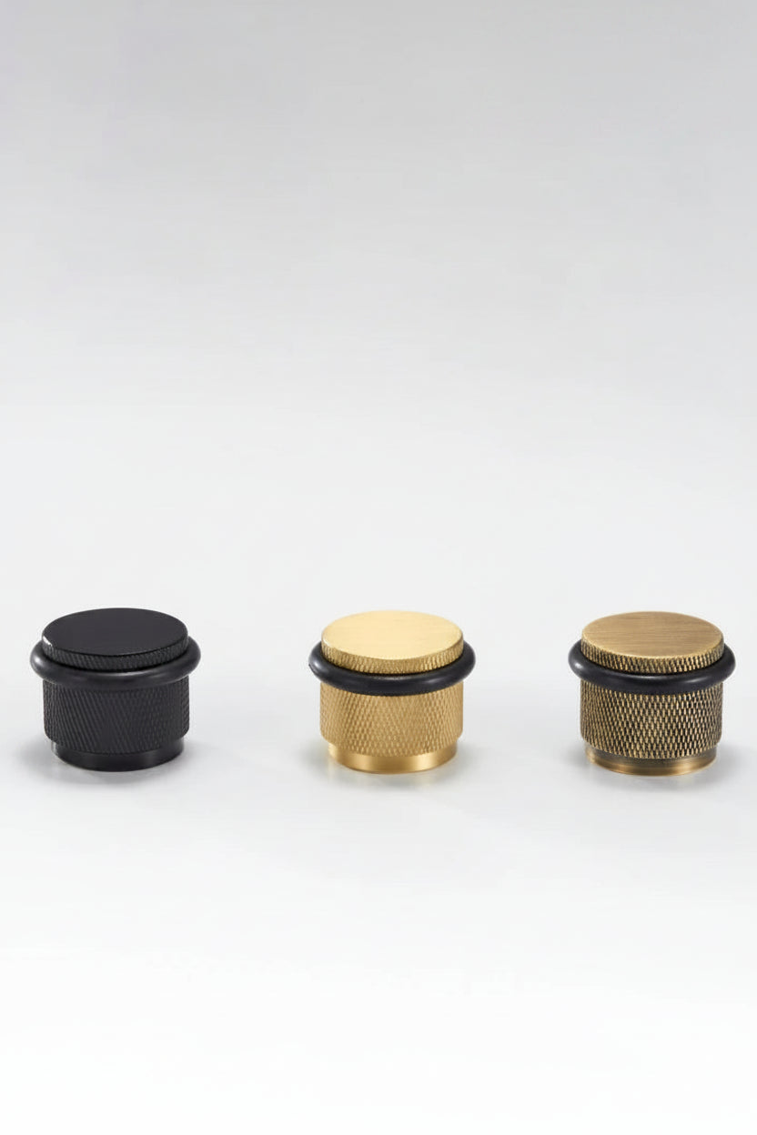 Set of four adjustable knurled floor door stops in black and gold finishes with black rings