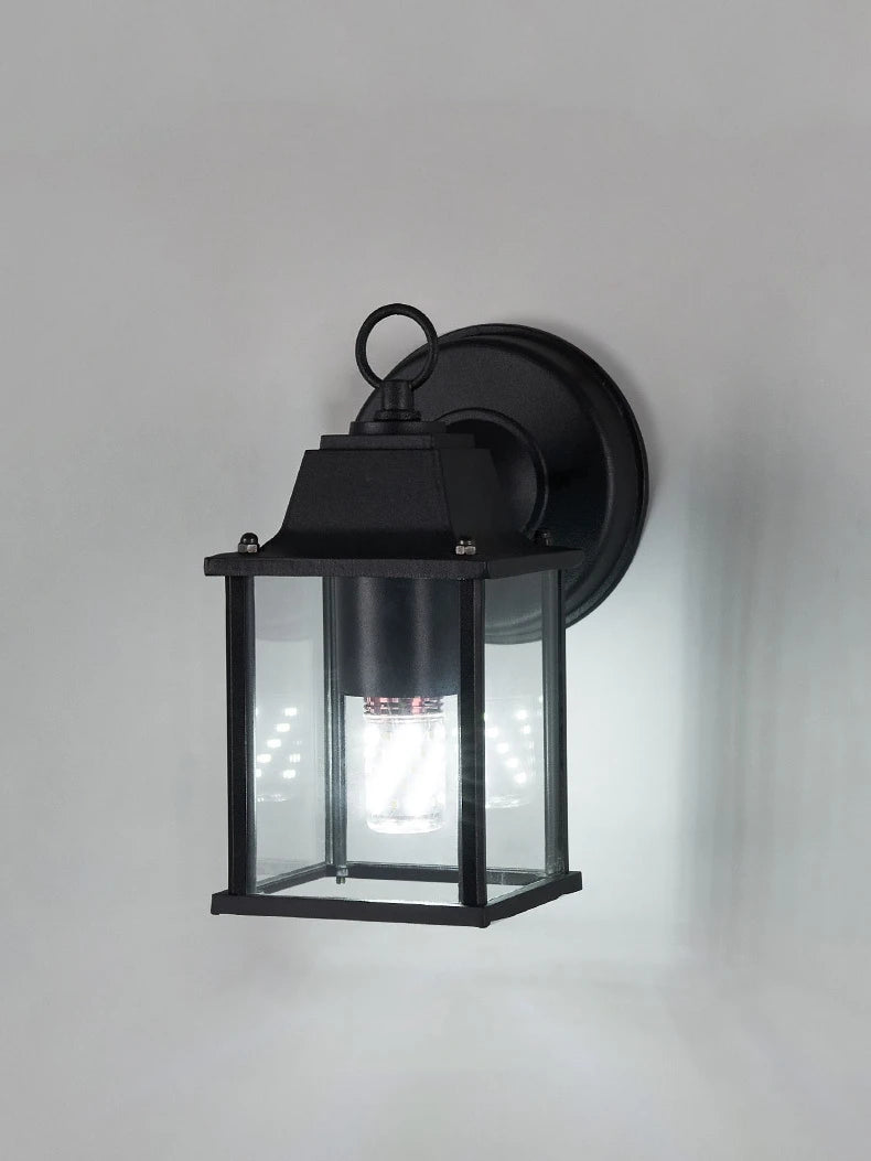 Black outdoor wall lantern light with clear glass and warm glowing bulb