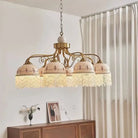 Gold multi-head pendant light with white ceramic shades, brown floral accents, tassel fringe on chain