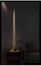 Adjustable LED zoom spotlight casting a narrow warm light beam on a console table plant