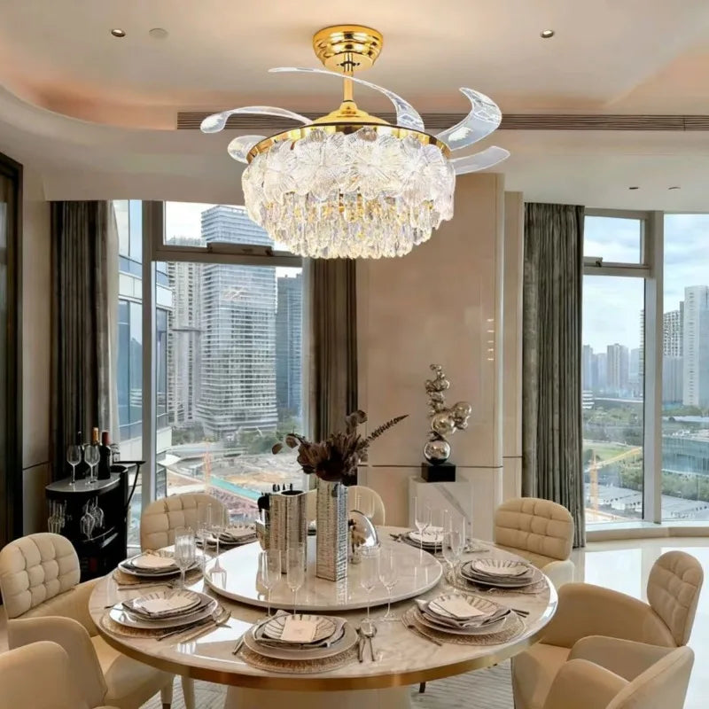 Gold ceiling fan with crystal glass light fixture and clear blades over dining table