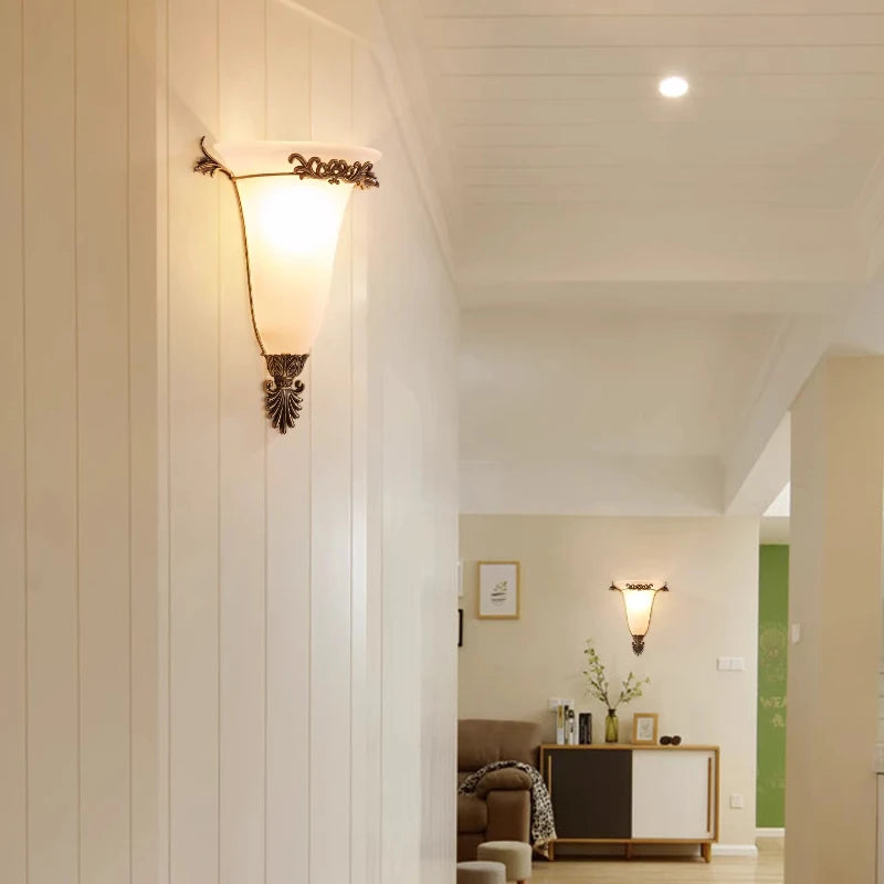Retro gold wall sconce with frosted glass shade and detailed metal leaf ornaments