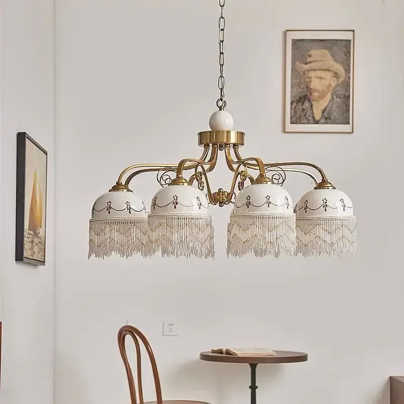 Gold multi-head pendant light with white ceramic shades, brown floral accents, tassel fringe on chain