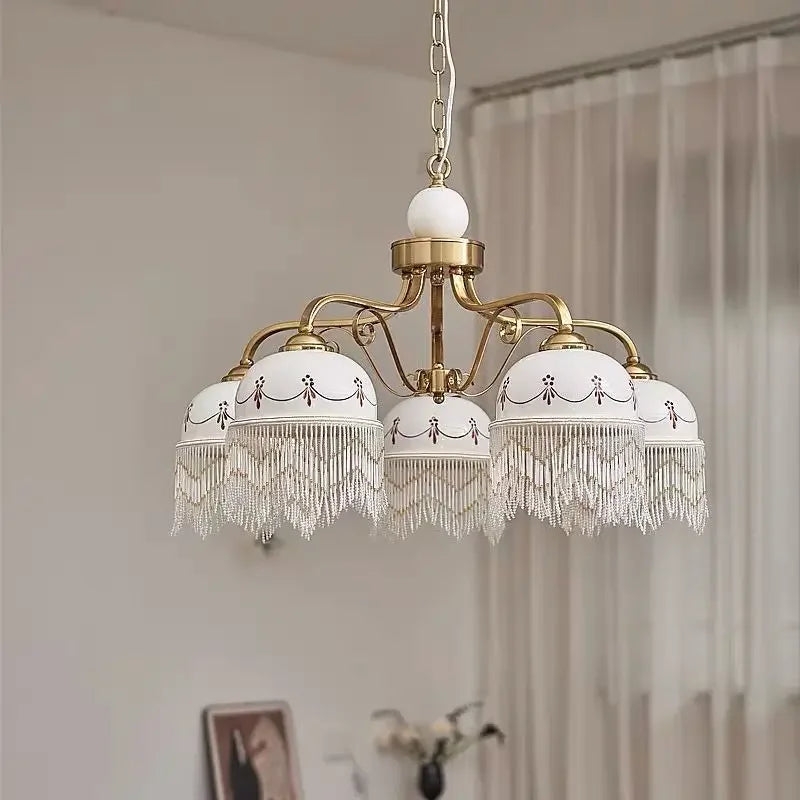 Gold multi-head pendant light with white ceramic shades and delicate tassel fringe on hanging chain