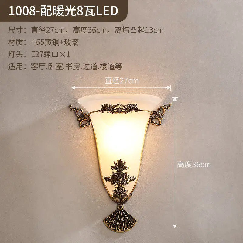 Decorative gold wall sconce with frosted glass shade and carved base ornament