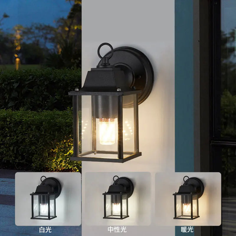 Black outdoor wall lantern light with clear glass sides and warm glowing bulb
